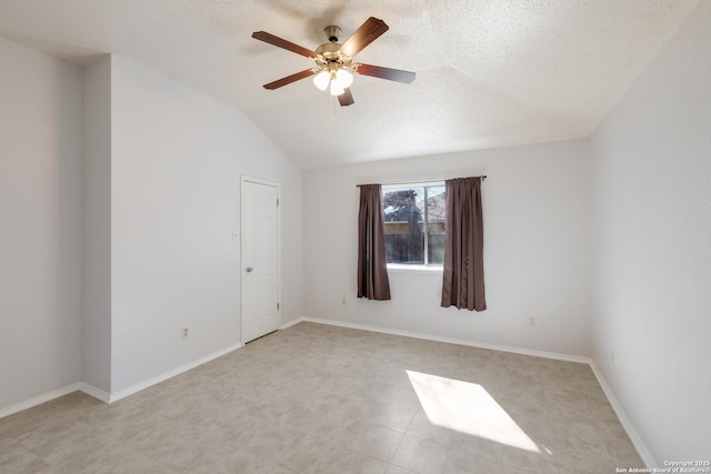 empty room with baseboards, a textured ceiling, a ceiling fan, and vaulted ceiling