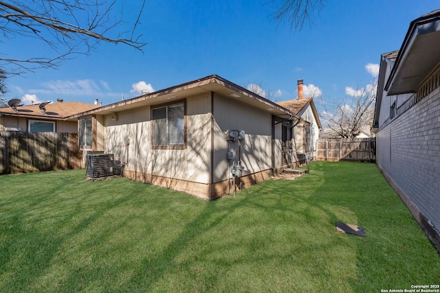 exterior space with central air condition unit, a lawn, and a fenced backyard