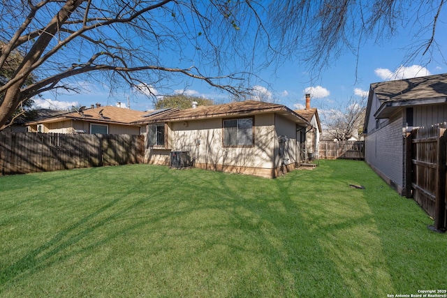 rear view of house with a fenced backyard, central AC unit, and a yard