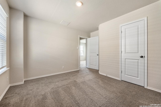 unfurnished bedroom featuring visible vents, carpet, and baseboards