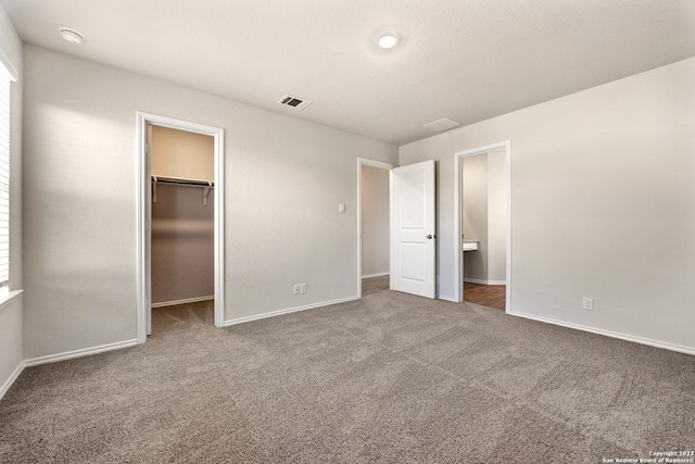 unfurnished bedroom featuring visible vents, a closet, carpet floors, baseboards, and a spacious closet