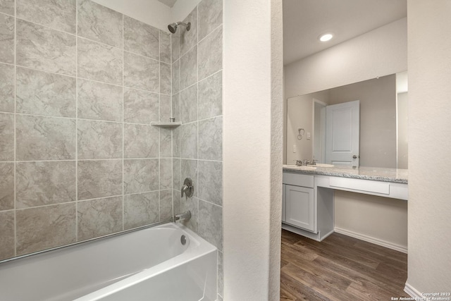 bathroom with tub / shower combination, vanity, baseboards, and wood finished floors