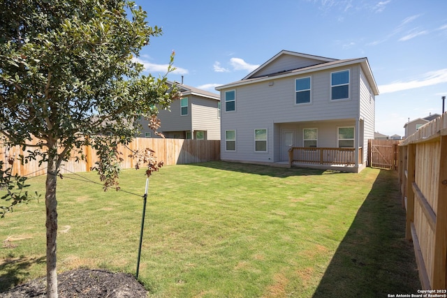 back of property with a yard, a wooden deck, and a fenced backyard