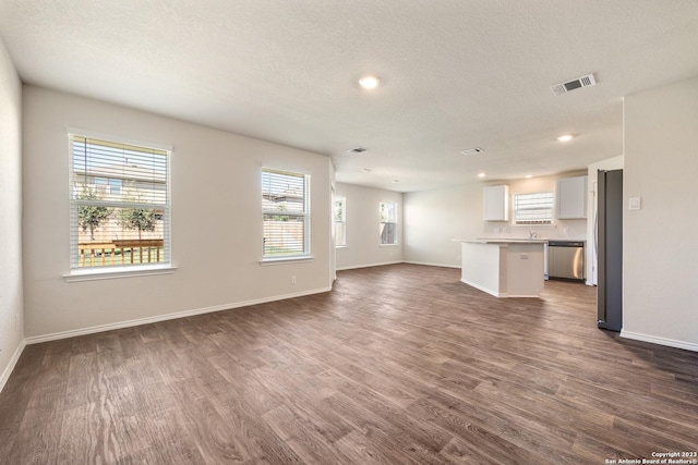 unfurnished living room featuring visible vents, baseboards, and dark wood-style flooring