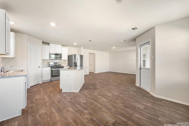 kitchen featuring visible vents, a sink, a center island, appliances with stainless steel finishes, and dark wood-style flooring