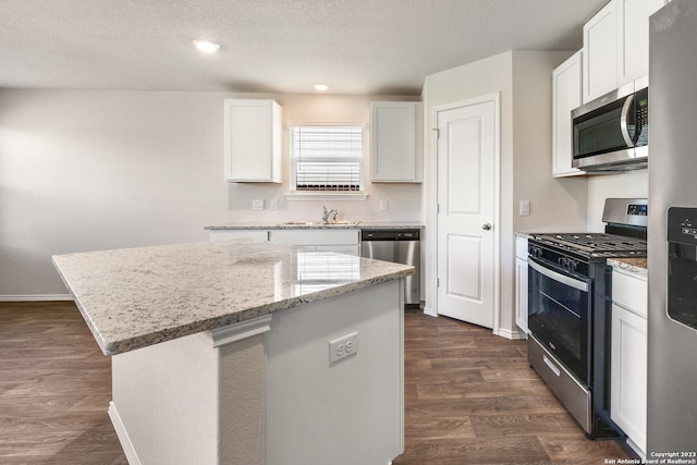 kitchen with a kitchen island, a sink, stainless steel appliances, dark wood-type flooring, and white cabinetry