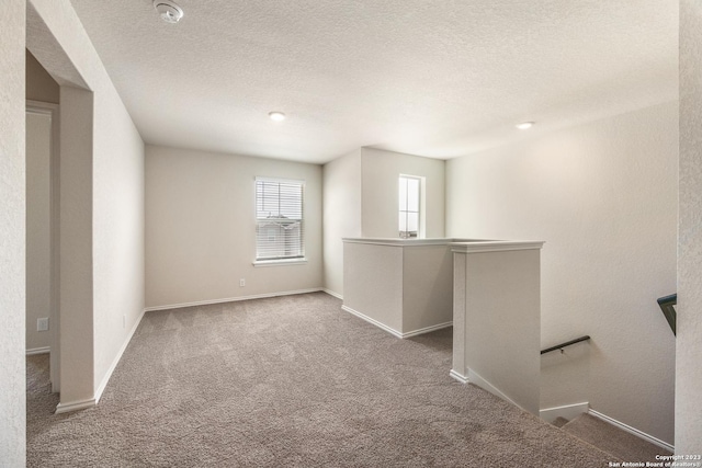 carpeted spare room featuring baseboards and a textured ceiling