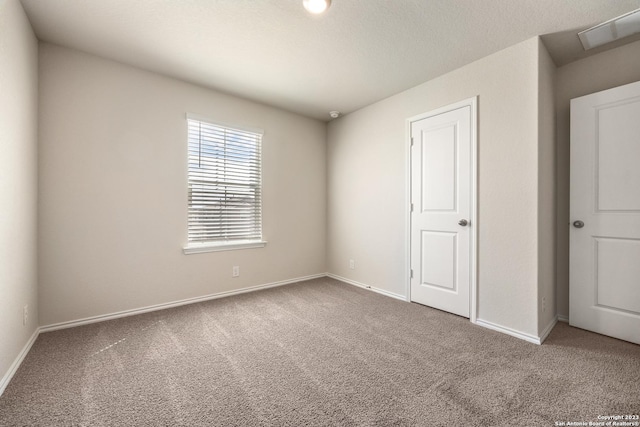 spare room with carpet, visible vents, and baseboards