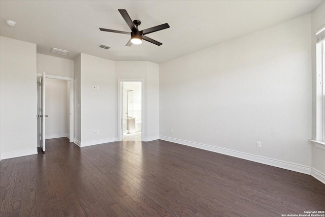 spare room with a ceiling fan, dark wood-style floors, visible vents, and baseboards