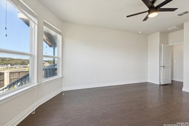 spare room featuring ceiling fan, visible vents, baseboards, and dark wood-style floors