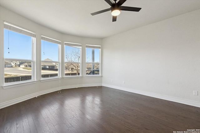 empty room with dark wood-style floors, ceiling fan, and baseboards