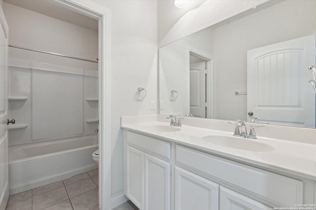 bathroom featuring tile patterned flooring, double vanity, toilet, and a sink