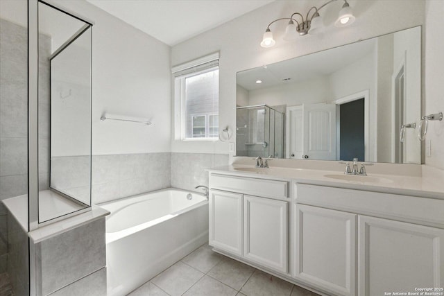 bathroom featuring tile patterned floors, a garden tub, a sink, a shower stall, and double vanity