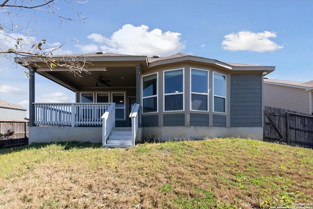 rear view of house featuring a yard, a porch, ceiling fan, and fence