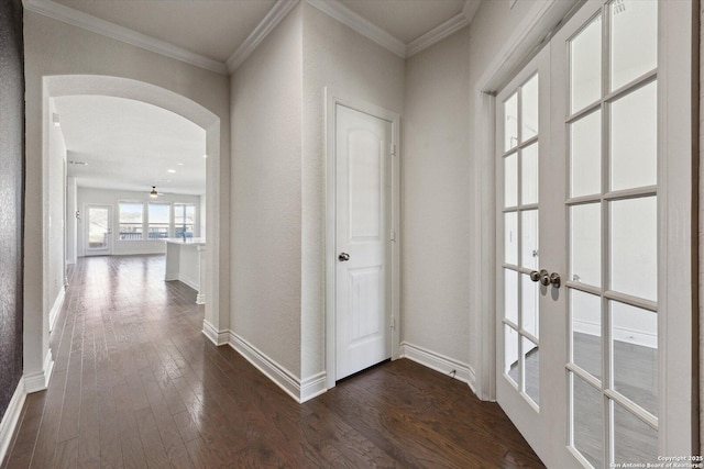 hall featuring arched walkways, crown molding, baseboards, and dark wood-style flooring