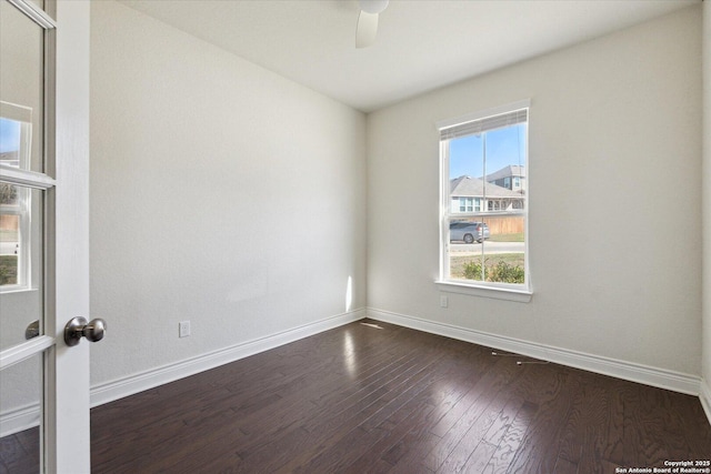 spare room featuring a ceiling fan, baseboards, and dark wood-style flooring