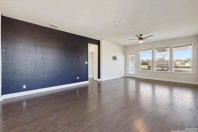 empty room featuring visible vents, a textured ceiling, wood finished floors, baseboards, and ceiling fan