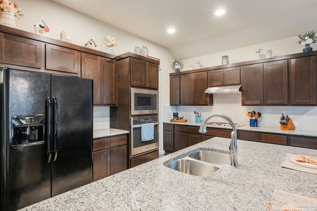 kitchen featuring dark brown cabinets, backsplash, under cabinet range hood, appliances with stainless steel finishes, and a sink