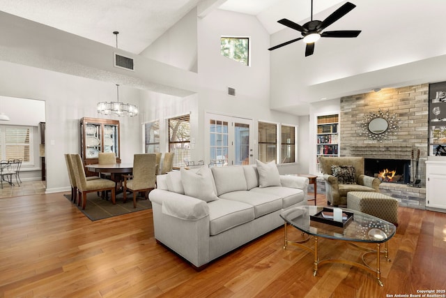 living room featuring visible vents, a brick fireplace, and wood finished floors