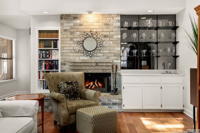 living room featuring indoor wet bar, built in features, light wood-style flooring, and a fireplace