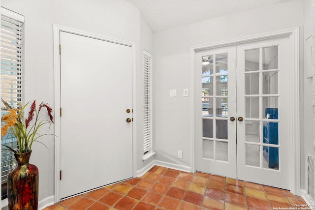 foyer with french doors, a textured ceiling, and tile patterned flooring