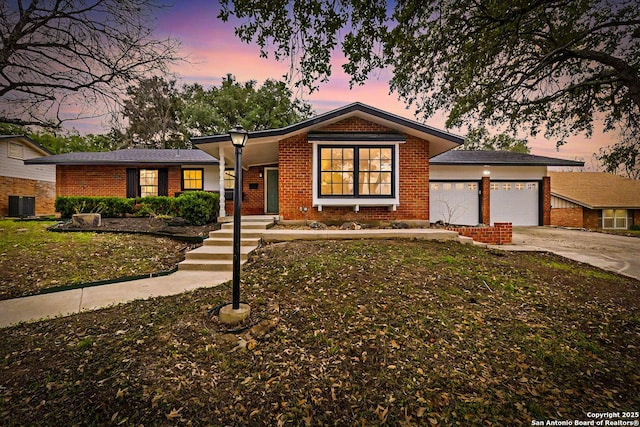 single story home featuring cooling unit, brick siding, concrete driveway, and an attached garage