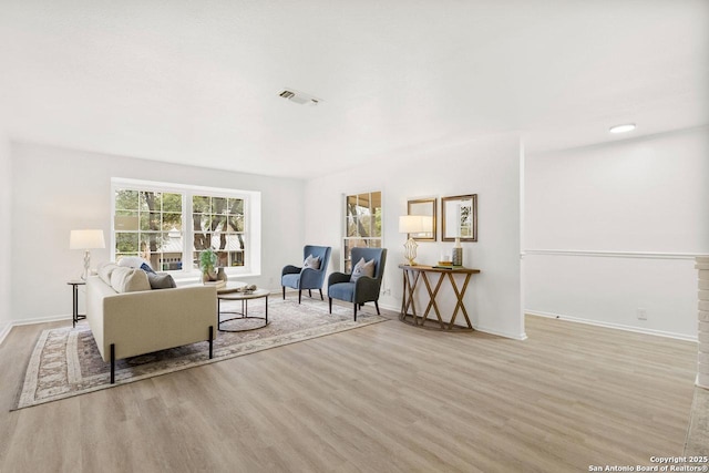 living area with visible vents, wood finished floors, and baseboards