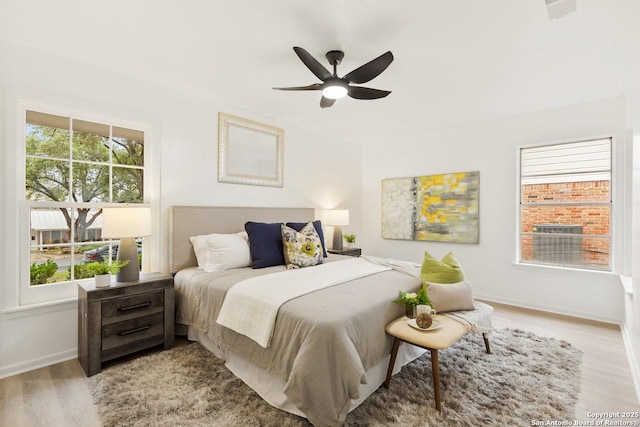 bedroom with visible vents, baseboards, light wood-style floors, and a ceiling fan