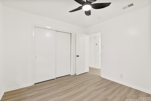 unfurnished bedroom with visible vents, light wood-style flooring, a ceiling fan, a closet, and baseboards