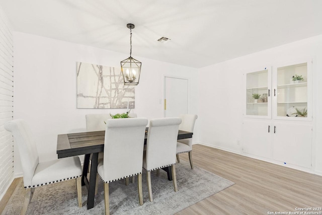 dining area featuring a notable chandelier, light wood-style floors, and visible vents