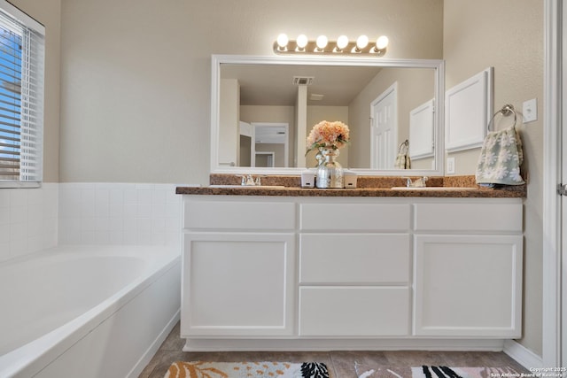 full bathroom with a bath, visible vents, a sink, and double vanity