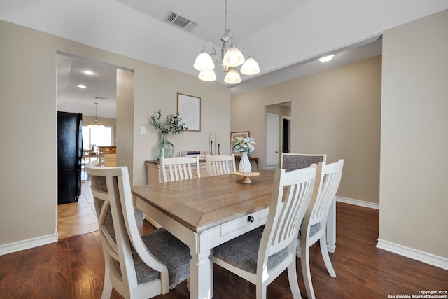 dining room with a chandelier, visible vents, baseboards, and wood finished floors