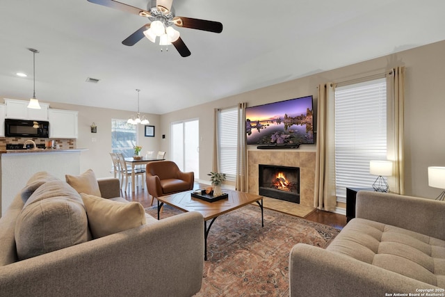 living room featuring visible vents, wood finished floors, a ceiling fan, and a tile fireplace