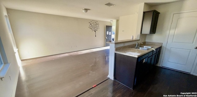 kitchen featuring a sink, visible vents, wood finished floors, and light countertops