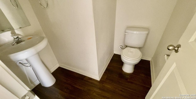 half bath featuring toilet, wood finished floors, and baseboards