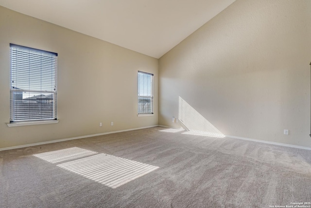 unfurnished room featuring baseboards, carpet, and high vaulted ceiling