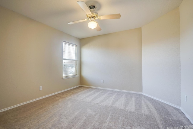 carpeted empty room featuring baseboards and a ceiling fan