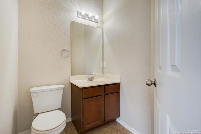 half bathroom featuring baseboards, toilet, vanity, and tile patterned flooring