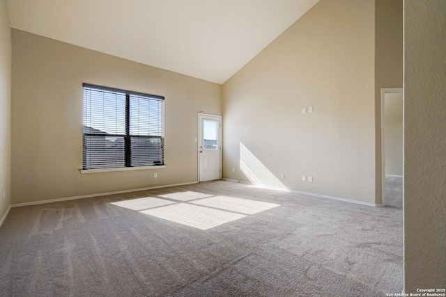 carpeted empty room with baseboards and high vaulted ceiling