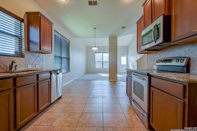 kitchen featuring light tile patterned floors, visible vents, a sink, stainless steel appliances, and brown cabinets