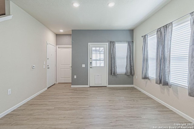 foyer with recessed lighting, baseboards, light wood-style floors, and a textured ceiling