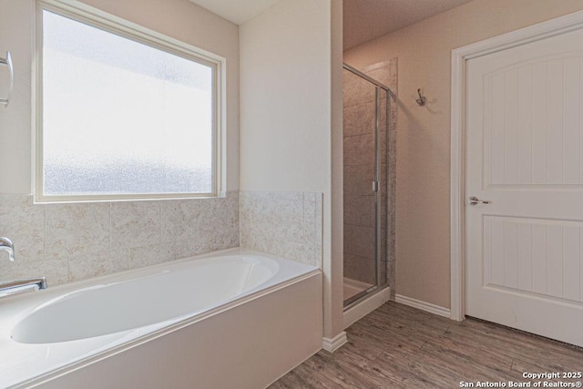 bathroom with a bath, a stall shower, and wood finished floors