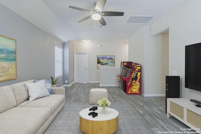 living room with visible vents, baseboards, wood finished floors, and a ceiling fan