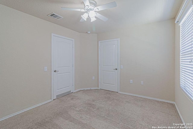 unfurnished bedroom with visible vents, multiple windows, baseboards, and carpet