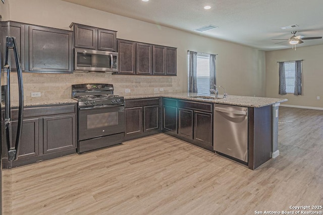 kitchen with black appliances, a sink, a peninsula, light wood finished floors, and dark brown cabinets