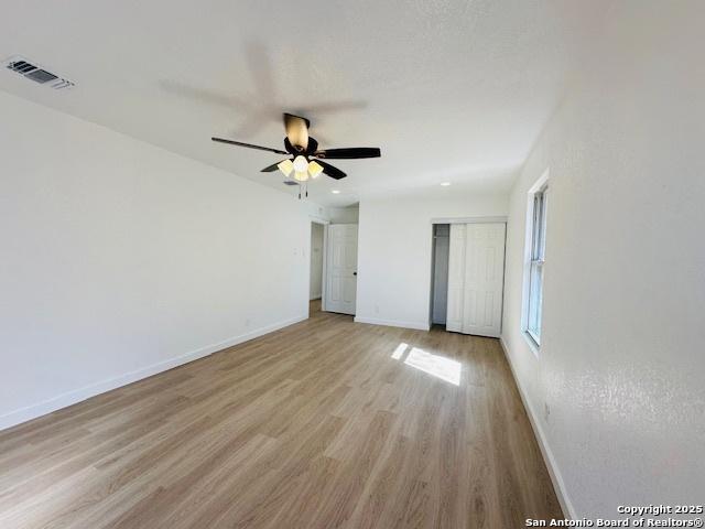 unfurnished bedroom with visible vents, light wood-style flooring, a closet, baseboards, and ceiling fan