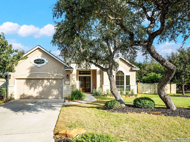 view of front facade with fence, concrete driveway, a front yard, french doors, and an attached garage