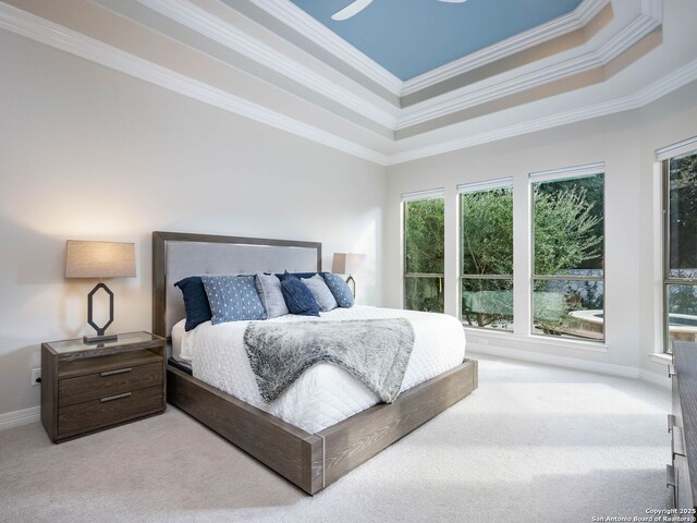 carpeted bedroom with a tray ceiling, crown molding, and baseboards