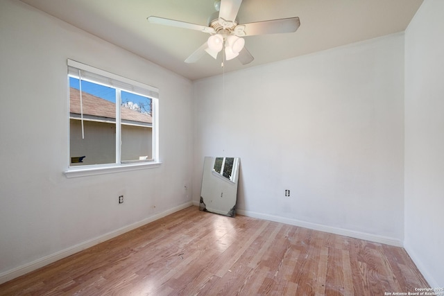 empty room featuring a ceiling fan, heating unit, wood finished floors, and baseboards