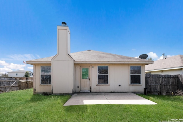 rear view of house with a patio, a lawn, a fenced backyard, and a chimney